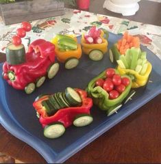 a blue plate topped with veggies shaped like cars and vegetables on top of it