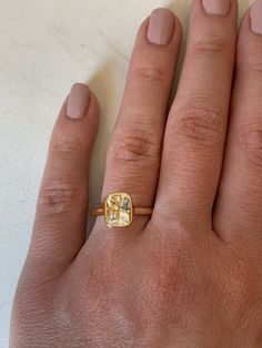 a woman's hand with a yellow diamond ring on it