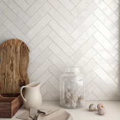 a kitchen counter with white herringbone tile on the back wall and wooden cutting board next to it