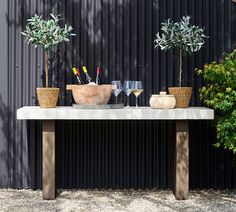 two potted plants on top of a table next to wine glasses and champagne flutes