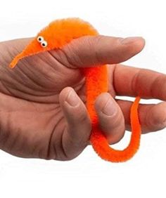 a hand holding an orange toy with eyes on it