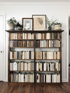 a bookshelf filled with lots of books next to a wall mounted planter