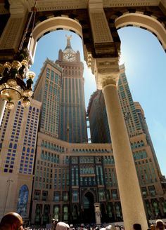 people are standing in the middle of a building with tall buildings behind them and a clock on top