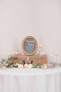 a table with candles, flowers and a chalkboard sign