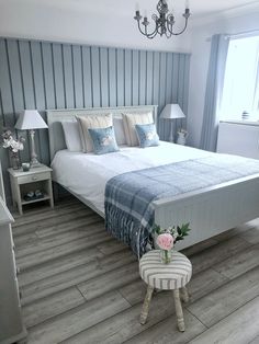 a white bed sitting in a bedroom on top of a hard wood floor next to a window