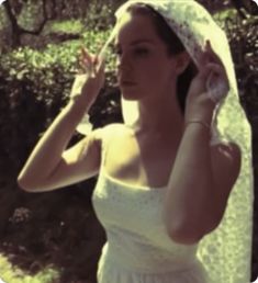 a woman in a wedding dress is holding her veil over her head