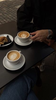 two cups of cappuccino and croissants are on the table