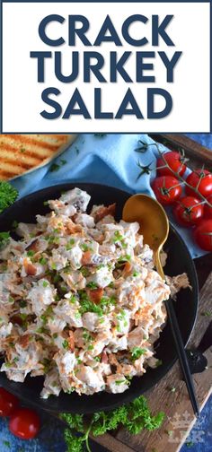 a bowl filled with chicken salad on top of a wooden cutting board next to tomatoes and bread