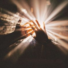 a person holding their hands out in front of a bright light that is shining down on them