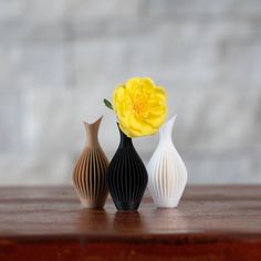 three vases with flowers in them sitting on a table