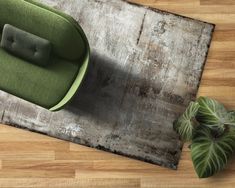 a green chair sitting on top of a wooden floor next to a potted plant