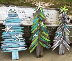 three wooden christmas trees sitting next to each other on top of a bench in the sand