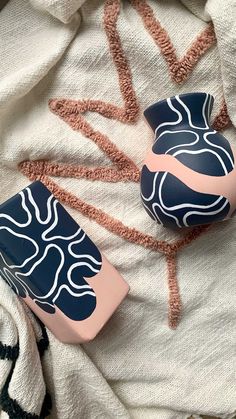 two blue and pink vases sitting on top of a white blanket next to each other