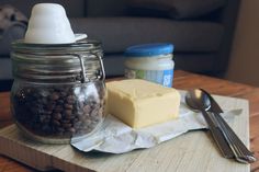 a wooden tray topped with lots of food next to a jar of butter and spoon