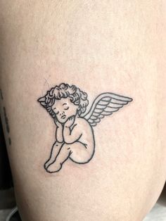 a small tattoo of an angel sitting on the back of a woman's thigh