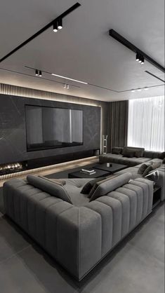 a modern living room with grey couches and a flat screen tv on the wall