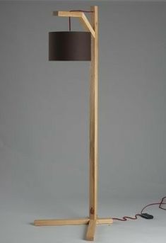 a wooden floor lamp with a black shade on the base and a cord connected to it