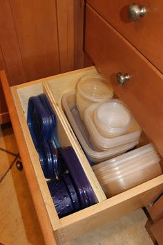 an open drawer in a wooden cabinet filled with containers