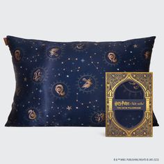 a blue pillow with gold stars and zodiac signs on it next to a decorative box