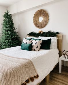 a white bed topped with pillows next to a christmas tree