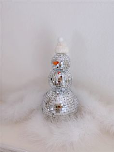 a snowman made out of disco balls sitting on top of a white fur covered floor