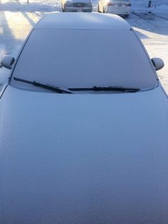 a car is covered in snow on the street