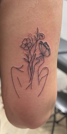 a woman's leg with flowers tattooed on the side and her hand holding it