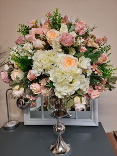 a vase filled with white and pink flowers on top of a gray table next to a mirror