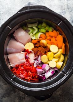 an overhead view of vegetables and meat in a slow cooker with the lid open