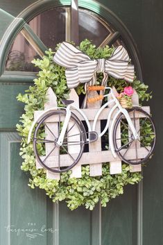 a bicycle made out of wooden crates with bows on the handlebars is hanging from a green door