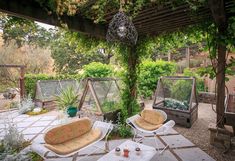 an outdoor patio with two chairs and plants on it, next to a pergolated area