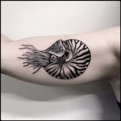 a woman's arm with a black and white tattoo design on her left arm