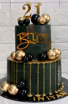 a two tiered cake with gold and black decorations