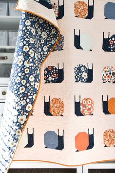 an orange and blue quilt is hanging on a white cabinet