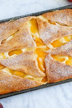 an apple pie sitting on top of a pan covered in powdered sugar next to apples