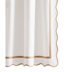 a white shower curtain with gold trimmings on the bottom and side panels, in front of a white background