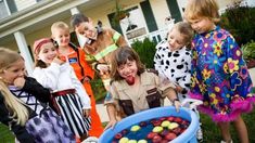 children in costumes are gathered around an ice cream sundae