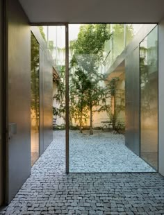 an open door leading into a courtyard with trees in the background and brick flooring