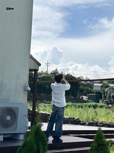 a man is standing on the steps looking at something in the air with his hand up to his head