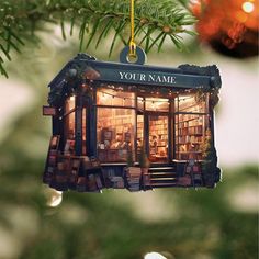 an ornament hanging from a christmas tree with bookshelves in the window