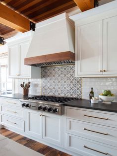 a kitchen with white cabinets and black counter tops is pictured in this image, there are two pots on the stove