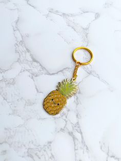 a pineapple shaped keychain with a smiley face on it sitting on a marble surface