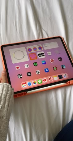 a person is holding an ipad in their hand on a white bed with the cover pulled down