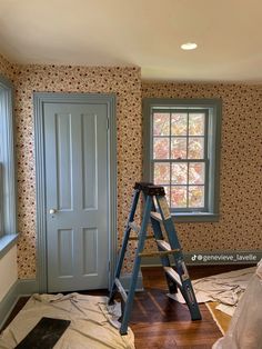 a ladder is in the corner of a room with floral wallpaper and blue doors