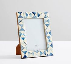 a blue and white photo frame sitting on top of a table