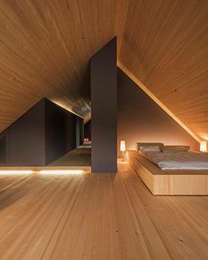 a bedroom with wooden floors and walls in an attic type building that is lit up at night