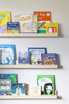 three wooden bookshelves with children's books lined up on the wall behind them