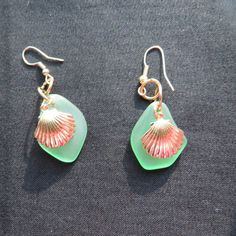 a pair of sea glass earrings with pink and green seashells