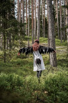 a woman walking through the woods with her arms outstretched