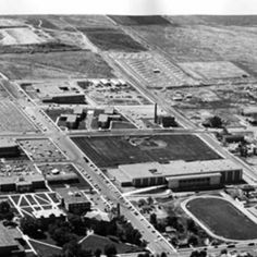 an old black and white photo of a baseball field in the middle of a town